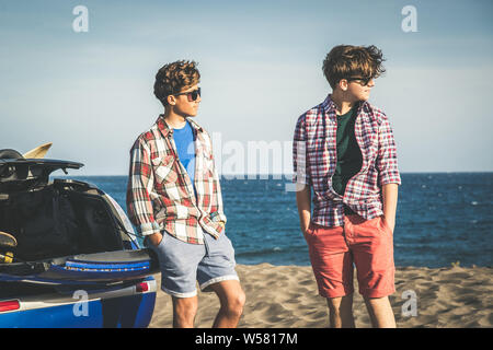 Deux jeunes adolescents heureux debout à la plage meilleurs amis en vacances bénéficiant d'une belle journée d'été. Beau gars à la mode petites amies d'attente nea Banque D'Images