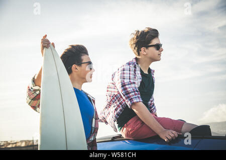Deux jeunes professionnels adolescent meilleurs amis souriant de planche de surf. Portrait de profil de deux professionnels des jeunes garçons à l'extérieur. Concept d'amitié et de partenariat