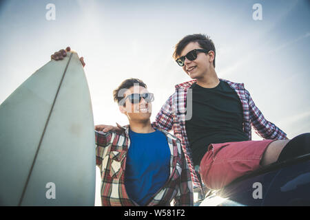 Deux jeunes professionnels adolescent meilleurs amis rire avec planche de surf. Libre de deux jeunes garçons heureux embrassant l'extérieur. Concept d'amitié et de partage s