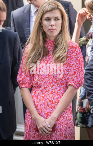 Boris Johnson's amie Carrie Symonds, en robe rose, attend à l'extérieur de 10 Downing Street pour l'arrivée du nouveau Premier Ministre Banque D'Images