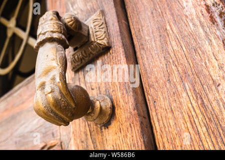 Ancien bouton en forme de main pour frapper sur une vieille porte en bois. Banque D'Images