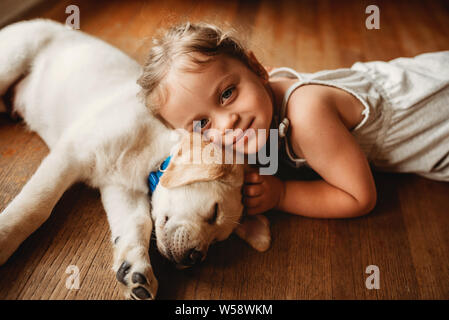 Labrador jaune lab puppy snuggling avec petite fille Banque D'Images