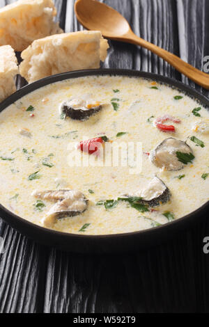 Soupe de poisson à la crème avec l'anguille, fromage et légumes close-up dans un bol sur la table verticale. Banque D'Images