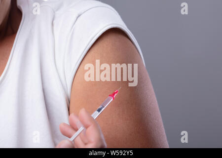 Patient Femme diabète Faire injection SERINGUE AVEC AIGUILLE sur sa main contre l'arrière-plan gris Banque D'Images