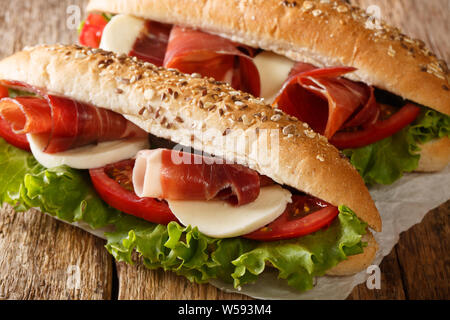 Les délicieux sandwichs avec du jambon prosciutto, mozzarella et légumes close-up sur la table horizontale. Banque D'Images