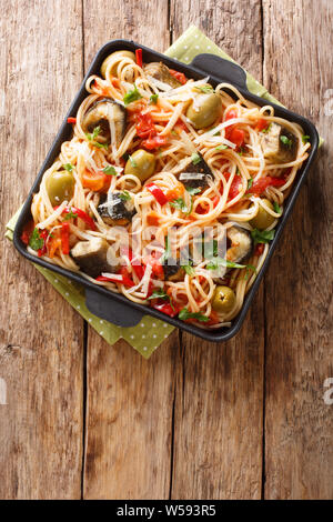 Les pâtes italiennes avec eel, olives, poivre et sauce tomate gros plan sur une assiette sur la table. Haut Vertical Vue de dessus Banque D'Images