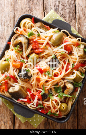 Spaghettis à l'anguille poisson frit, des olives, du poivre et de la sauce tomate sur une assiette sur la table. Haut Vertical Vue de dessus Banque D'Images