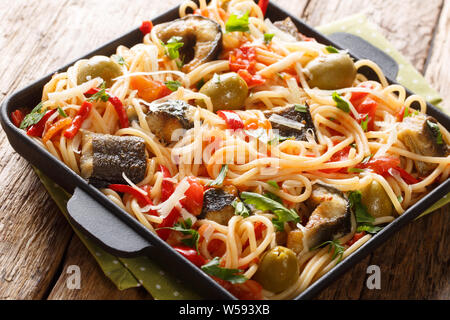 Pâtes méditerranéenne avec des poissons avec de l'anguille grillée, olives, poivre et sauce tomate close-up sur une plaque sur la table horizontale. Banque D'Images