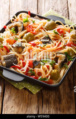 Délicieux spaghetti à l'anguille frite, olives, poivre et sauce tomate libre sur une plaque verticale sur la table. Banque D'Images