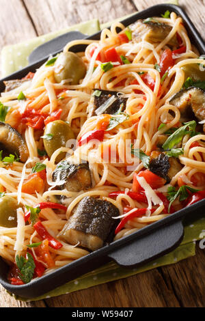 Les pâtes italiennes avec eel, olives, poivre et de la sauce tomate sur une plaque verticale sur la table. Banque D'Images