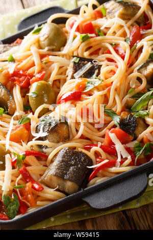 Spaghetti à l'anguille, les olives et la sauce tomate sur une plaque verticale sur la table. Banque D'Images