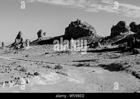 Formations Rock casting shadows, chemin de terre menant à travers un désert aride terrain désertique. Noir et blanc. Banque D'Images