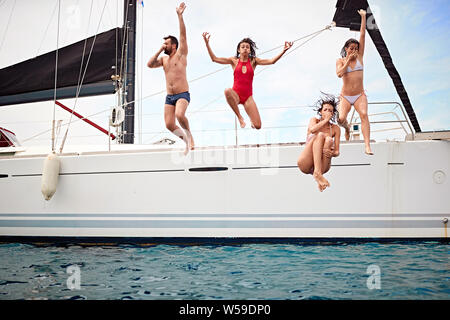 Groupe de gens heureux sautant dans l'eau au cours d'un voile Banque D'Images