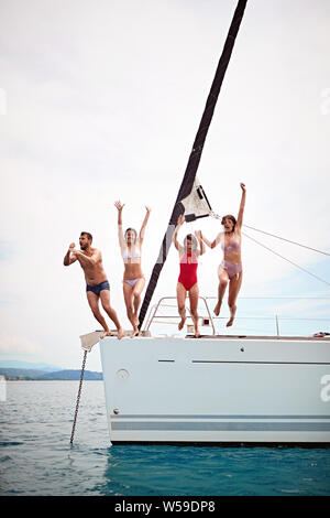 Groupe d'amis heureux sautant dans l'eau au cours d'un voile Banque D'Images