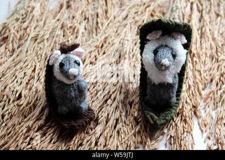 Deux souris mignon fixer pour se détendre sur fond de paddy de la gerbe à la main, laine tricot petit rat produit à partir de fils dans le temps libre Banque D'Images