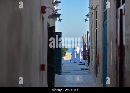 AL WAKRAH (Qatar) - 5 février 2016 : Trois hommes qatari balade sur le front de mer de Wakrah vieux souk. Prise à la fin d'un après-midi d'hiver Banque D'Images