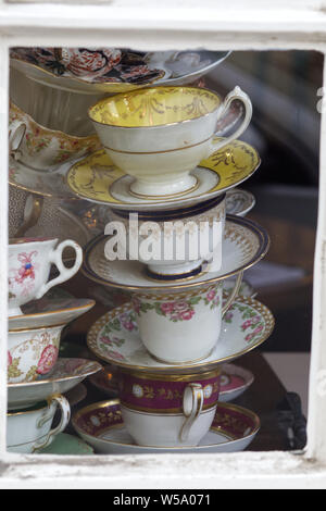 Empilées, tasses et soucoupes en porcelaine, dans une fenêtre Banque D'Images