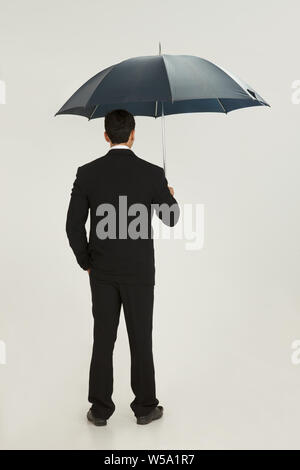 Vue arrière d'un homme debout sous un parapluie Banque D'Images