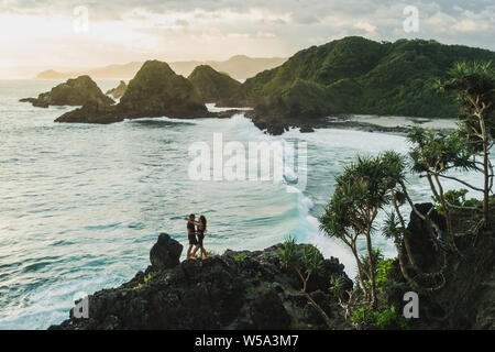 L'homme et la femme à la recherche d'uns les autres avec amour au coucher du soleil avec l'océan et sur la montagne. Travel concept, vue panoramique tourné, wanderlust. Banque D'Images