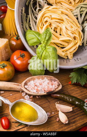 La composition avec les ingrédients pour la cuisson des tagliatelles à la tomate, basilic frais, huile d'olive et parmesan. Banque D'Images