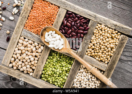 Sélection de légumes secs dans les compartiments en bois sur une table en bois rustique Banque D'Images