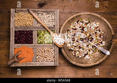 Sélection de légumes secs dans les compartiments en bois sur une table en bois rustique Banque D'Images