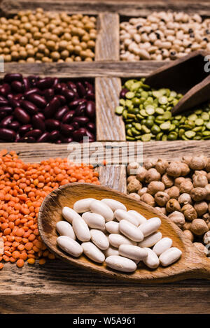 Sélection de légumes secs dans les compartiments en bois sur une table en bois rustique Banque D'Images