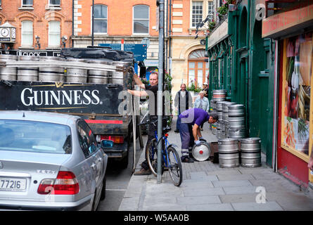 La livraison de la bière Guinness à pub à Dublin. Déchargement de camion Man de barils, tandis que d'autres rouleaux vers l'ouverture au sol Banque D'Images