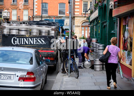 La livraison de la bière Guinness à pub à Dublin. Déchargement de camion Man de barils, tandis que d'autres rouleaux vers l'ouverture au sol Banque D'Images