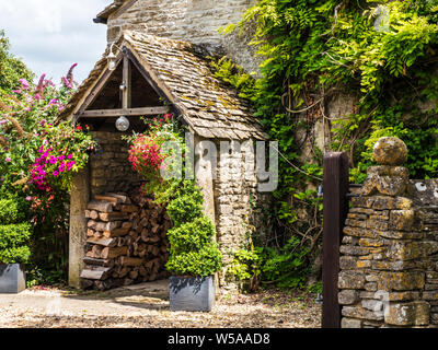 Un joli porche utilisé comme un journal store sur un cottage en pierre dans la région des Cotswolds. Banque D'Images