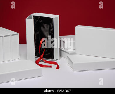 Cadeaux blanche avec doublure en soie noire et ruban rouge sur fond rouge Banque D'Images