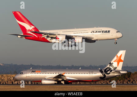 Airbus A380 de Qantas grandes quatre passagers équipés d'avions qui atterrissent à l'aéroport de Sydney alors qu'un avion Jetstar est sur la piste. Banque D'Images