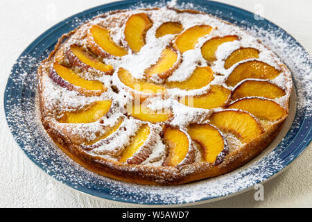 Tarte aux pêches. Gâteau fait maison avec des tranches de pêches sur une plaque Close Up on White Background Banque D'Images