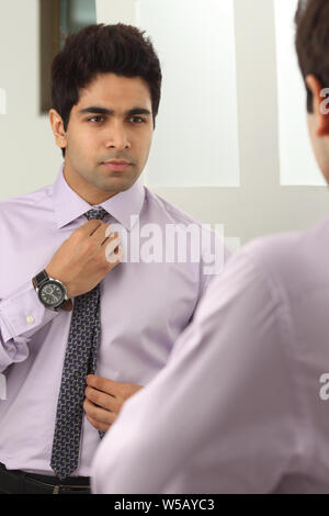 Businessman adjusting tie in mirror Banque D'Images