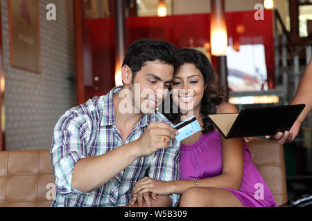 Couple payant la facture par carte de crédit dans un restaurant Banque D'Images