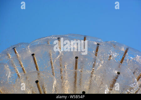 Fontaine avec des projections d'eau tombe en face de bleu ciel clair, fontaine de ball ressemble à un pissenlit fond d'été Banque D'Images