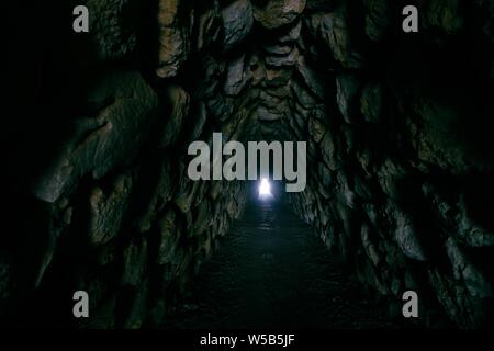 Rocky couloir dans une grotte avec une lumière au fin Banque D'Images