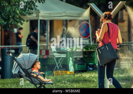 Prague, le 27 juillet 2019. Mère refroidit bien en public mist machina au parc sous la vague de chaleur de l'Europe Banque D'Images