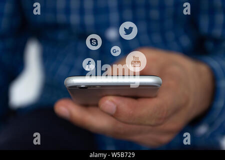 Image main d'hommes de l'utilisation d'un smartphone avec icônes de réseaux sociaux. Le concept de communication à travers les réseaux sociaux. Banque D'Images