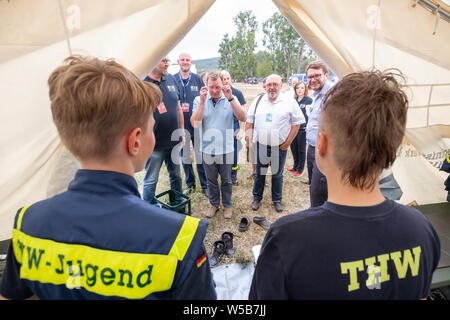 Rudolstadt, Allemagne. 27 juillet, 2019. Bodo Ramelow, Linke (M), premier ministre de la Thuringe, parle avec de jeunes assistants dans une tente du Camp de jeunes 2019 Fédéral THW. Environ 5000 jeunes de toute l'Allemagne en concurrence à l'échelle fédérale des jeunes Camp de l'organisme de secours technique (THW) dans les premiers secours, soins des blessures et de la transformation du bois des compétitions. Crédit : Michael Reichel/dpa/Alamy Live News Banque D'Images