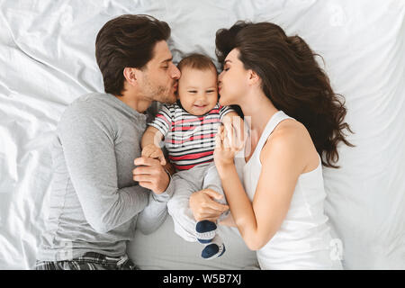 Happy caucasian couple kissing joues douces de leur bébé adorable fils Banque D'Images