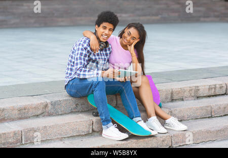 Couple of teenagers sitting on stairs with digital tablet Banque D'Images