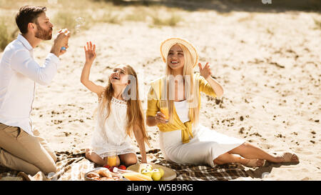 Les parents avec fille soufflant des bulles de savon dans la nature Banque D'Images