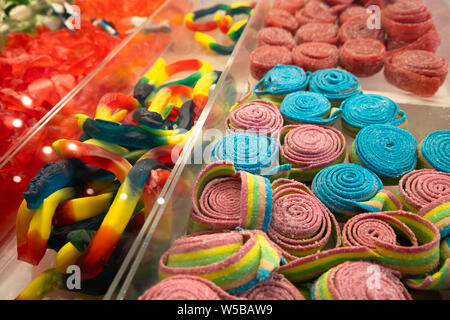 Assortiment coloré de bonbons gommeux et ceintures aigres exposés dans des bacs en plastique transparent dans un magasin de bonbons ou un cadre de marché Banque D'Images
