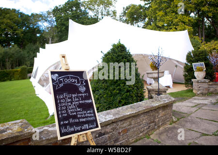 Un pavillon de mariage pour les invités et un tableau noir avec un calendrier écrit d'événements mariage, selective focus Banque D'Images