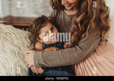 Close up portrait of young girl smiling while mère tient son Banque D'Images