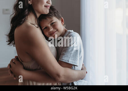 Fils d'âge scolaire d'être embrassé par mère de lumière naturelle studio Banque D'Images