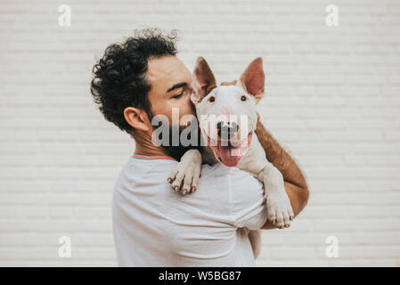 Homme barbu embrassant un chien bull terrier blanc Banque D'Images