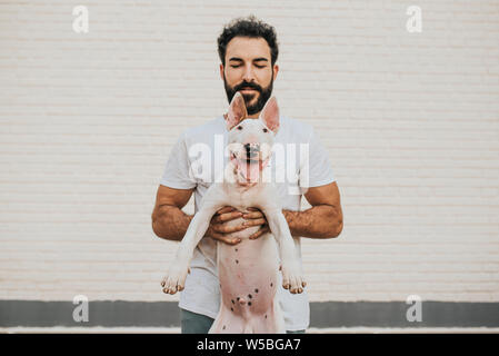 Homme barbu tenant une bull terrier chien regardant la caméra Banque D'Images