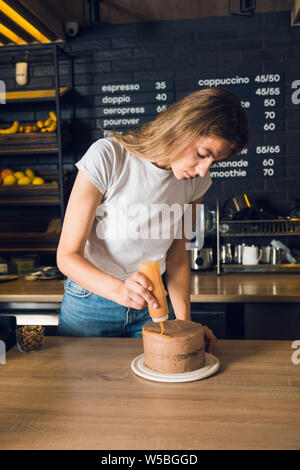 Belle femme blanc T-shirt la décoration de gâteau au chocolat avec un cara Banque D'Images